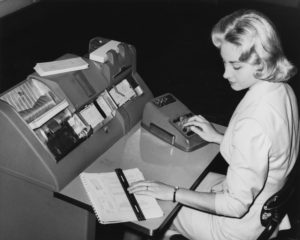 Woman entering data into old computer system as example of vendors.